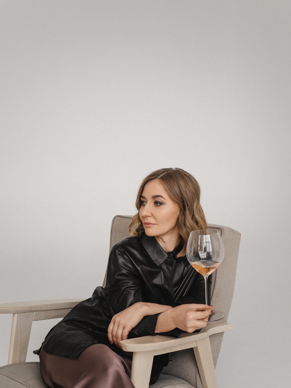Liubov Leonova seated in an armchair, holding a glass of rosé